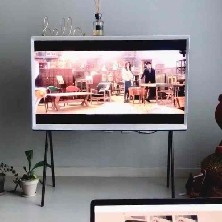 白とグレーのトーンが特徴のリビング、ザ・セリフ QLED テレビ43インチと植物が配置されたモダンなインテリア