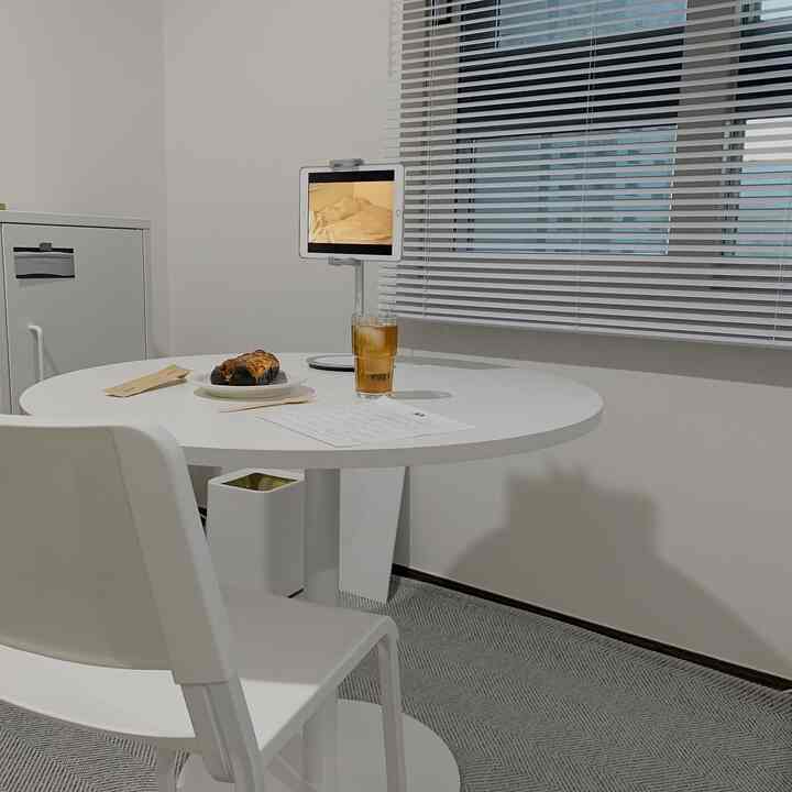 White interior with round table, white chair, and blinds in a compact home cafe setting