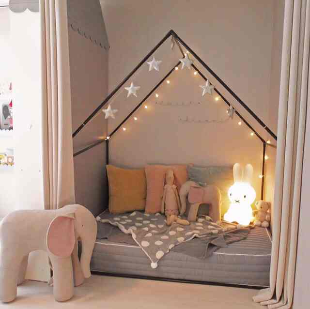 ナチュラルカラーの子供部屋、遊び人形やクッション、ムードランプが配置された雰囲気ある空間