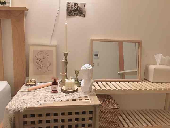 Natural-toned studio apartment featuring a vanity and nightstand decorated with candles and framed art, creating a cozy interior