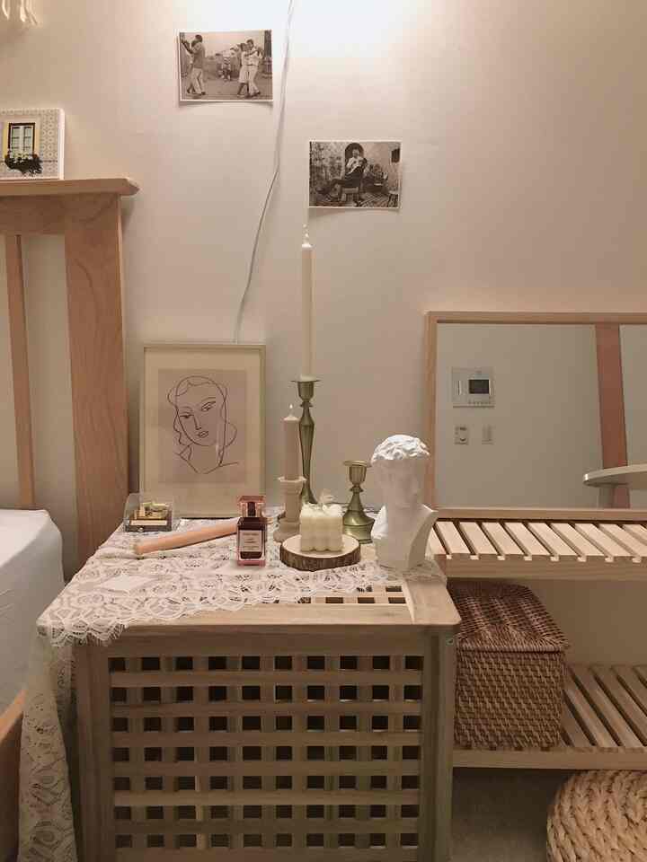 Cozy bedroom space featuring natural wood tone vanity and nightstand decorated with vintage accessories