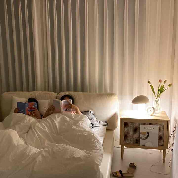 Beige-toned living room featuring cream sofa and white bedding with two kids reading books, creating a cozy atmosphere
