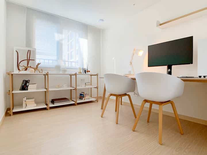 Minimal study space with white tones and wood furniture, presenting a clean interior that feels spacious