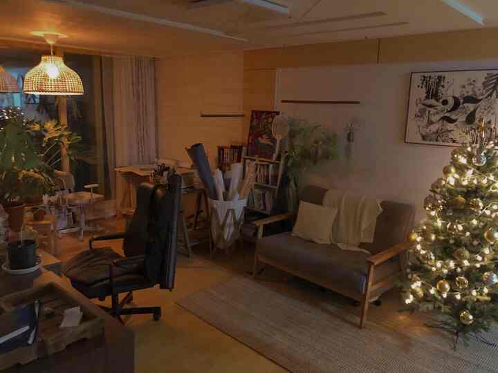 Warm natural-tone living room and home office space featuring Christmas tree and pendant lights, creating a cozy atmosphere
