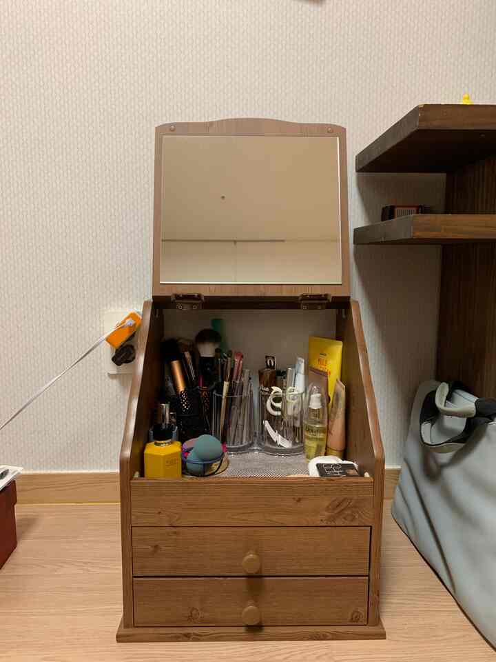 ナチュラルな木目調のコンパクトな部屋にミニ化粧台と整頓された化粧品が配置された雰囲気のあるインテリア