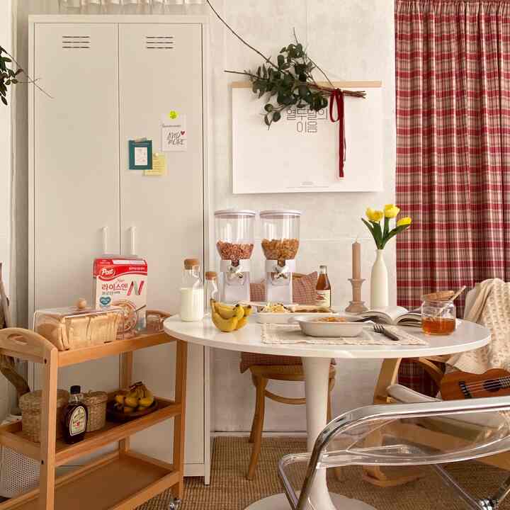 Ivory and wood tone veranda home cafe featuring a round dining table with cereal dispensers, milk bottle, and bananas in a warm atmosphere