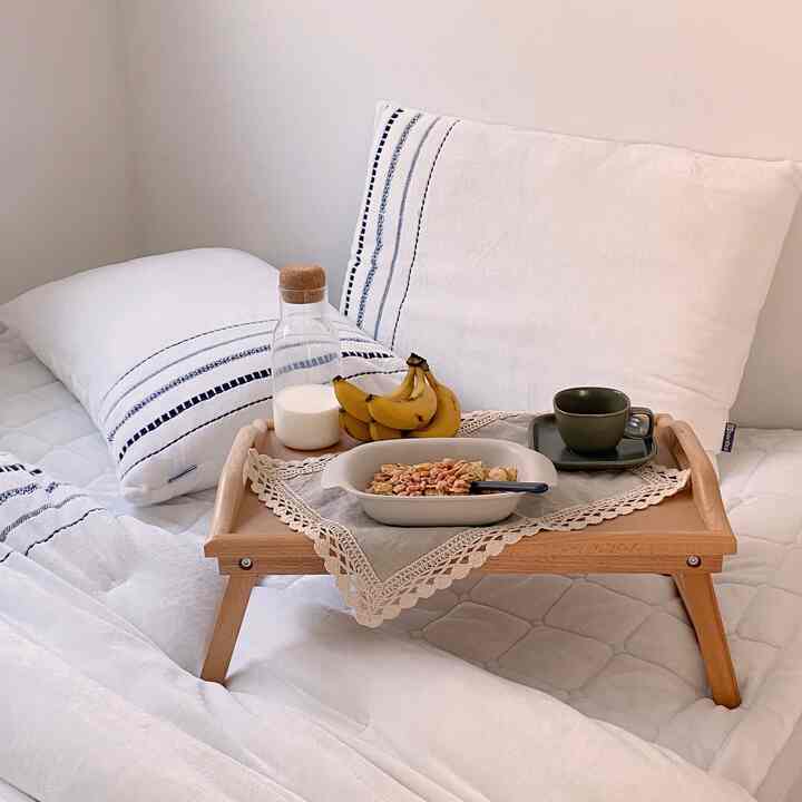 White-toned bedroom featuring a wooden bed tray with lace placemat creating a cozy atmosphere