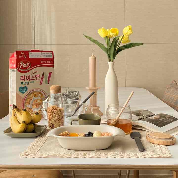 アイボリーと黄色の調和が取れたダイニングルーム、テーブル上に花瓶、キャンドル、食べ物や飲み物が配置された雰囲気のあるおうちカフェスペース