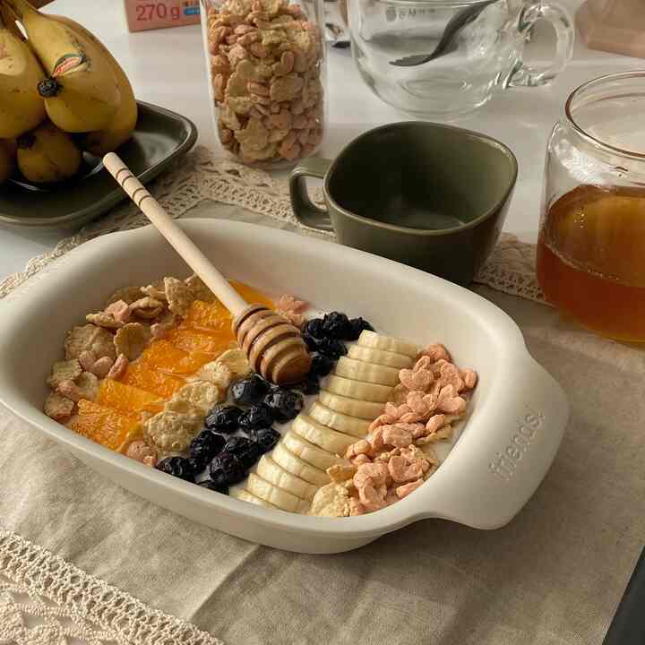 Beige-toned dining table featuring home cafe dishware with fruits and honey in a cozy setting