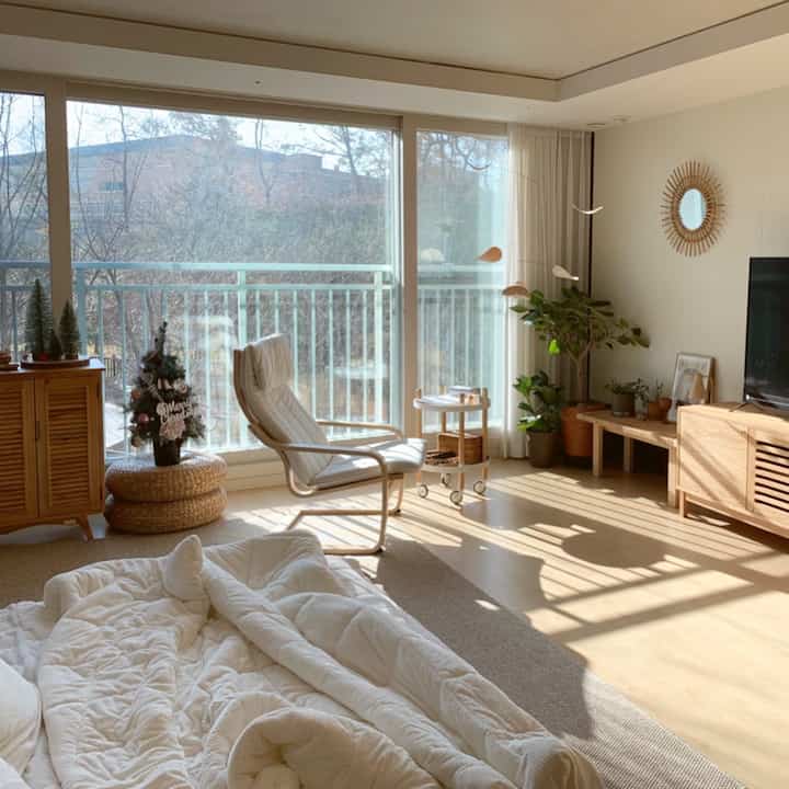 A sunlit living room with warm natural colors and wood tones, featuring a cozy armchair, curtains, and a rug creating a comfortable atmosphere