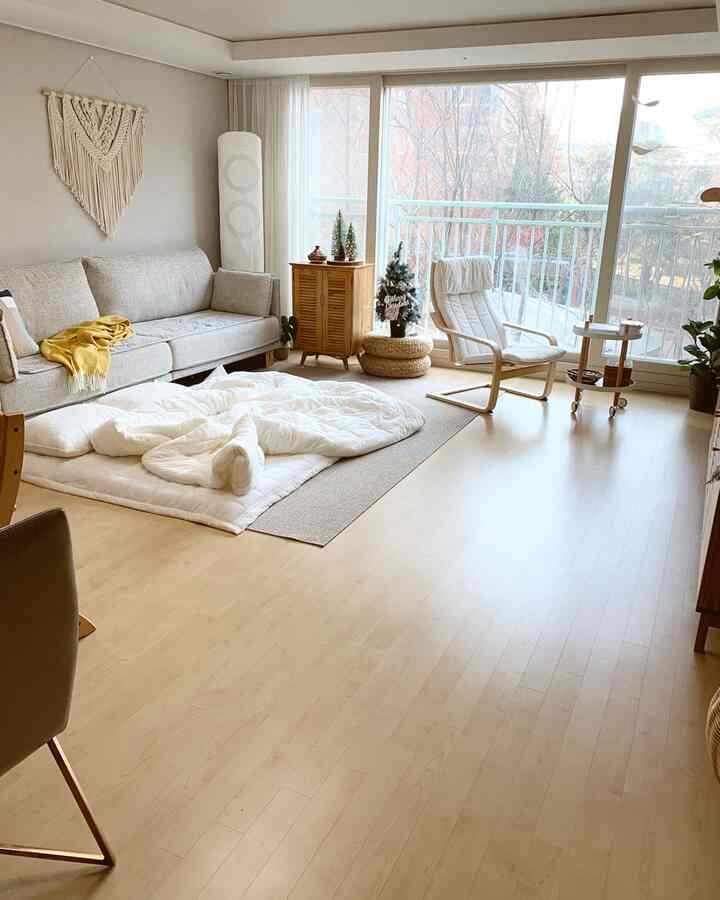 Bright white and beige toned living room featuring a comfortable sofa, armchair, and cozy microfiber duvet on the floor