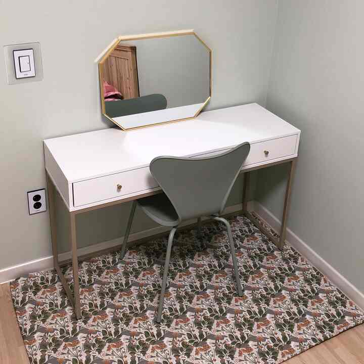 パステルグリーンとホワイトの調和が美しい狭い部屋の化粧台空間、シンプルな家具とゴールドの鏡が配置された印象的なインテリア