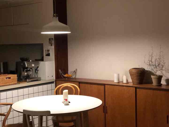 A cozy dining room featuring brown wood furniture, white dining table light, and a coffee machine
