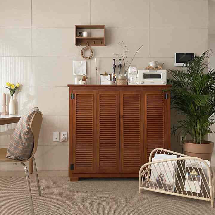 A cozy home cafe space featuring ivory walls and natural wood-toned furniture, with a rattan magazine rack and large potted plant