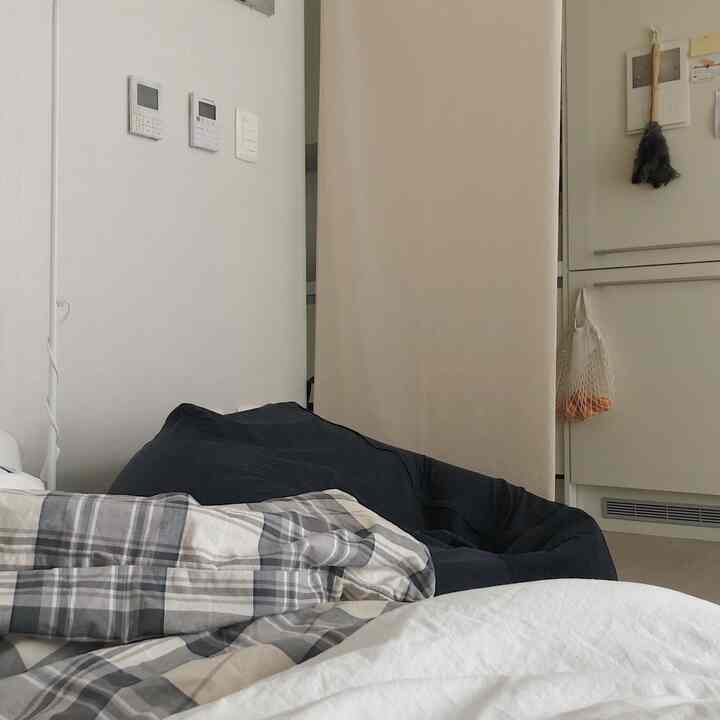 Bedroom space featuring gray checked duvet cover and beige room divider, with a cozy and warm atmosphere