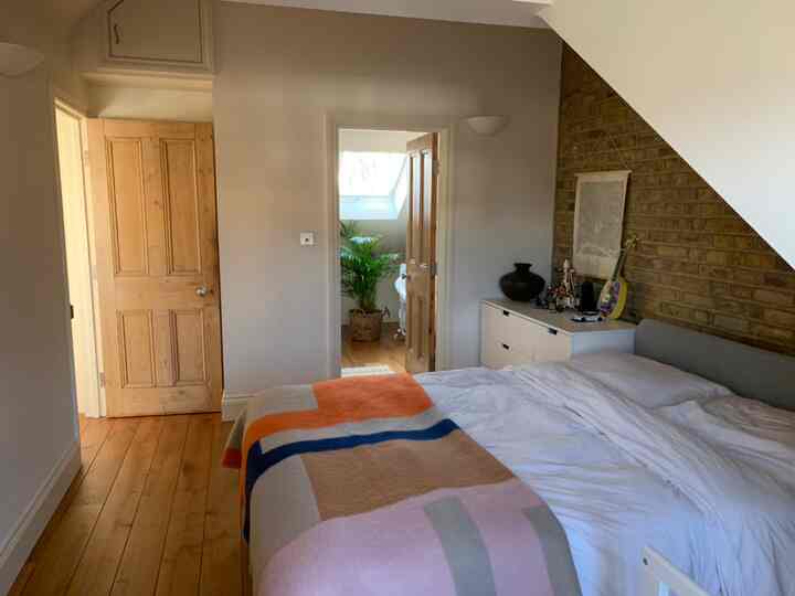 White and brown toned loft bedroom featuring large bed, dresser, and decorative brick wall atmosphere