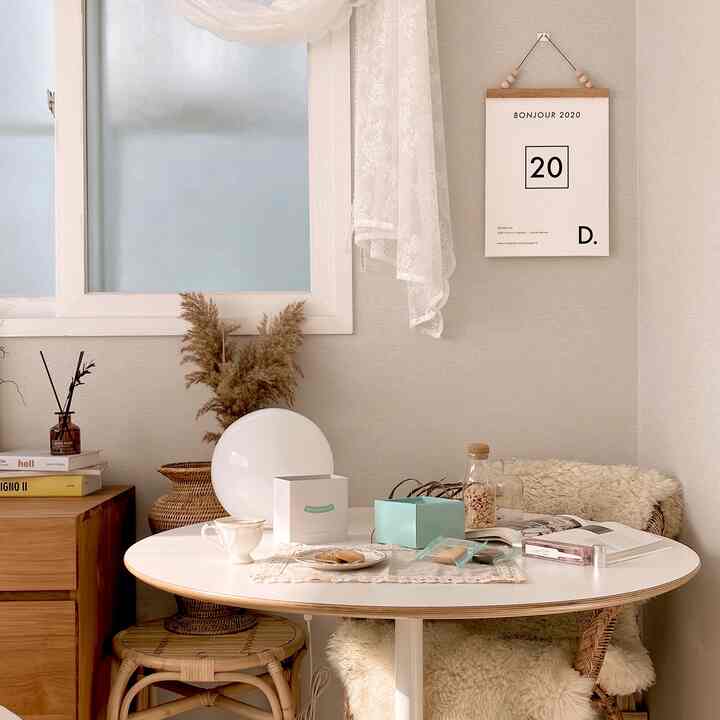 Natural beige and wood tone bedroom corner featuring a rattan chair and white round table creating a cozy home cafe atmosphere