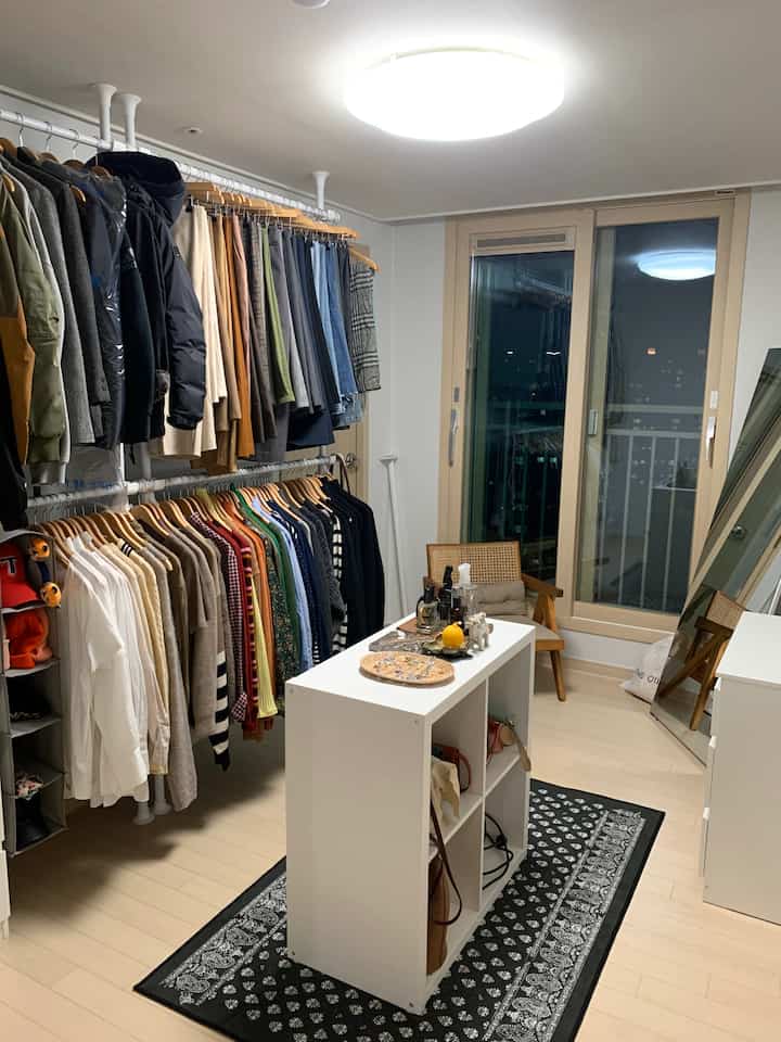 A white and wood tone walk-in closet featuring wooden hangers and a central storage unit in a tidy arrangement