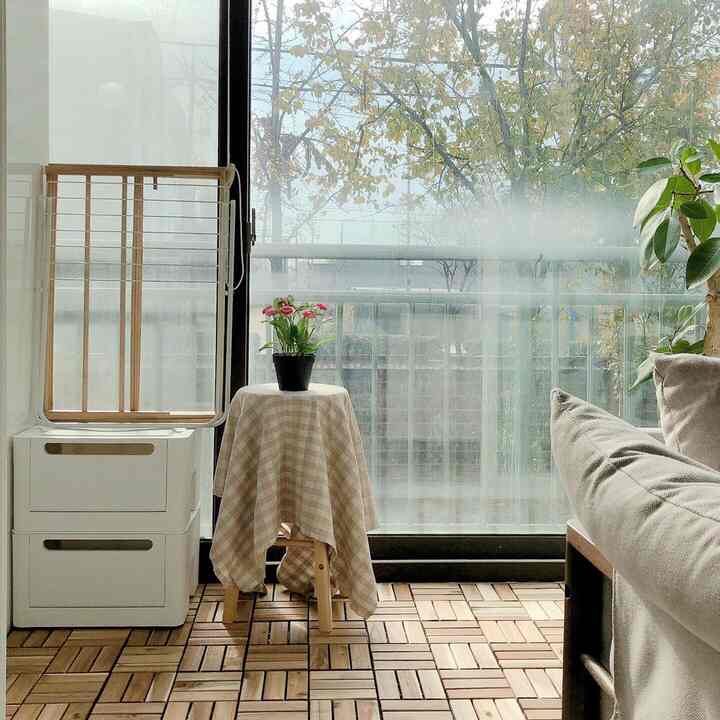 Bright wood tone flooring and beige table runner on a small veranda space featuring natural light and plants creating a cozy atmosphere