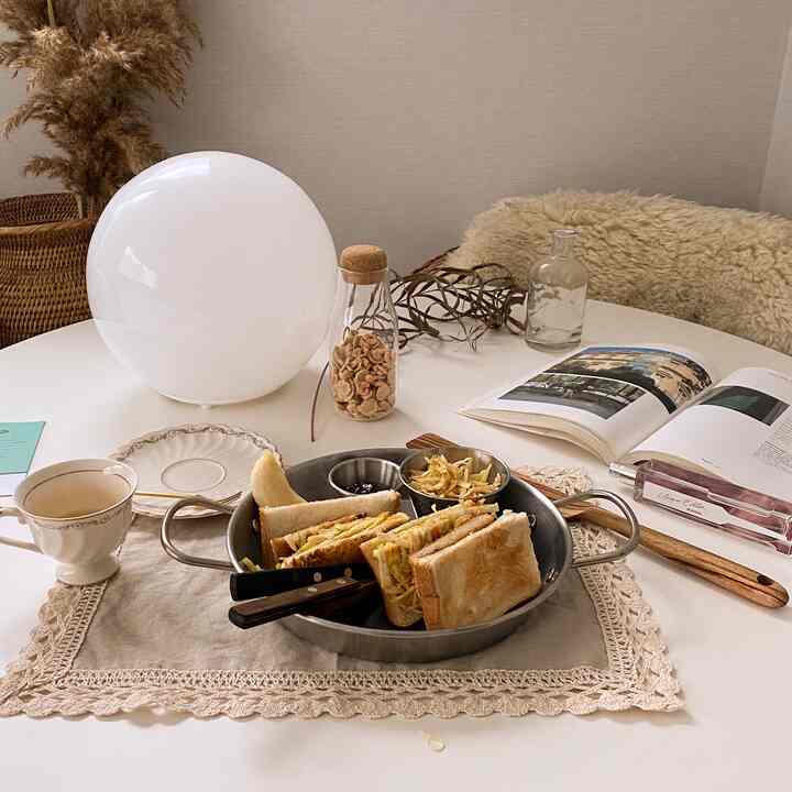 Cozy bedroom corner home cafe featuring a white round table with beige accents and brunch items