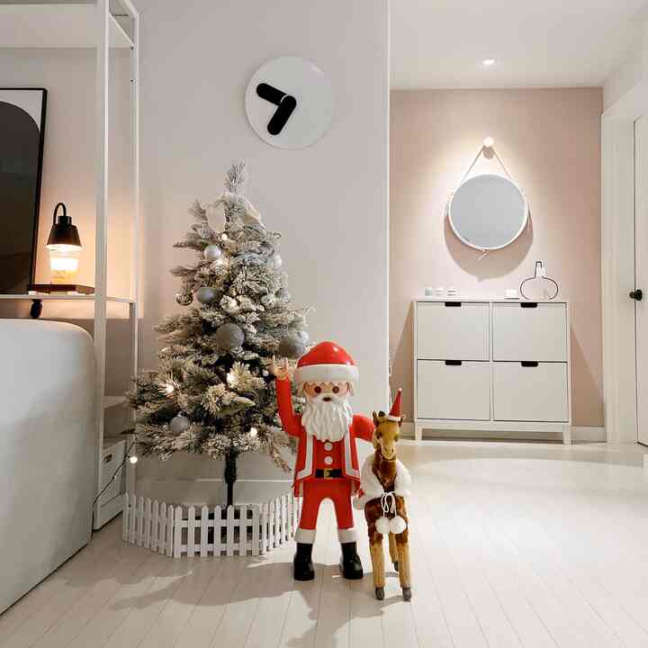 白と茶色のトーンが特徴のリビング、クリスマスツリーとサンタの人形、キリンのぬいぐるみが配置された温かみのある自然な空間