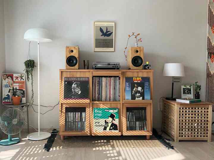 Natural living room with white walls and central wooden storage table, featuring LP records and audio equipment for a relaxed atmosphere
