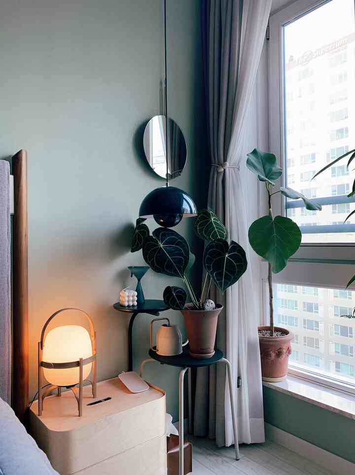 A natural wood-toned bedroom corner with green plants and cozy lighting, featuring Nordic style decor