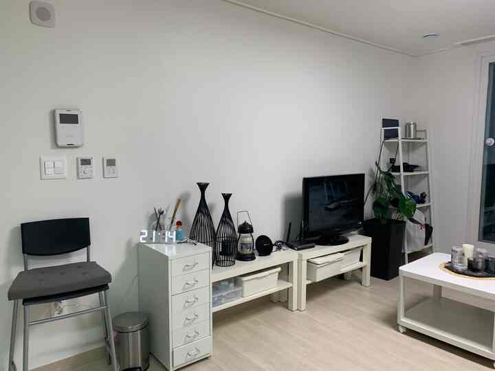 A white and natural color toned living room featuring modular furniture and plants with a simple, cozy atmosphere