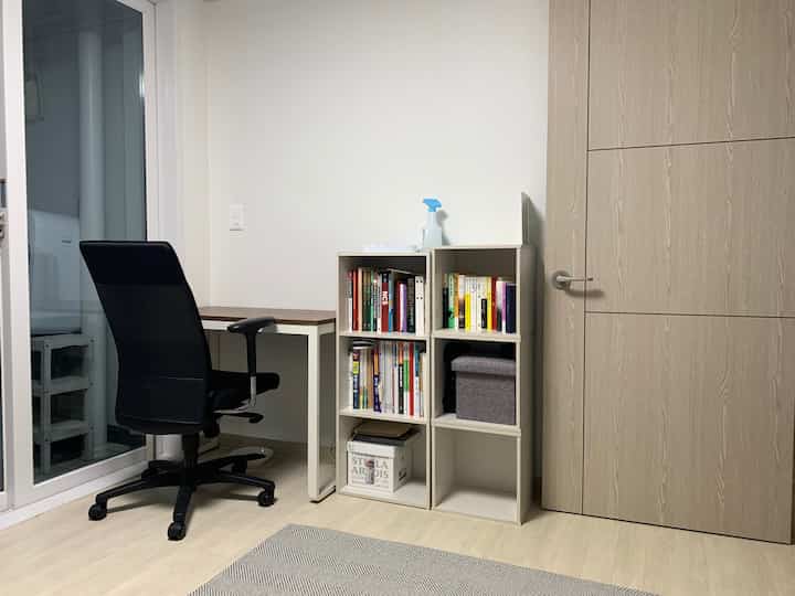White and brown toned home office space featuring desk and bookshelf with a clean work environment