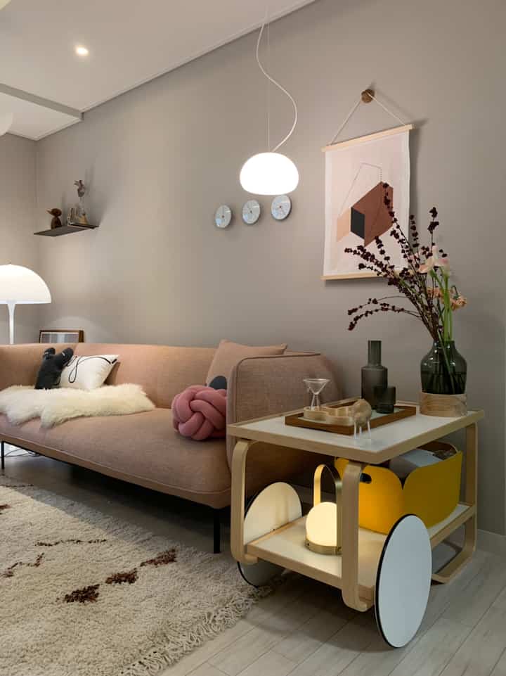 Natural beige-toned living room featuring a brown sofa, wooden side table, and ambient lighting in a cozy Nordic interior style