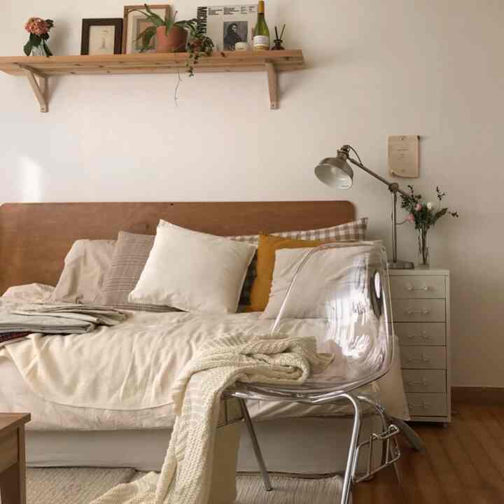 Soft beige and natural brown-toned bedroom featuring a transparent chair and vintage-style floor lamp creating a cozy atmosphere