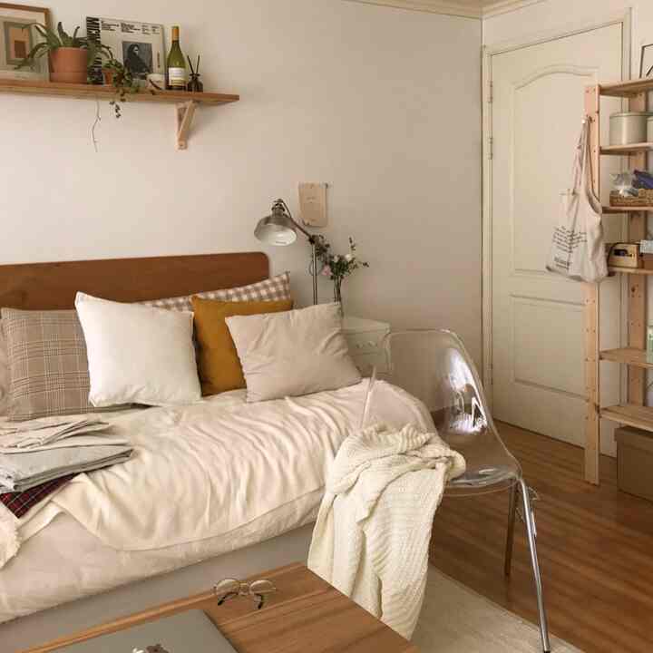 White and beige toned living room featuring a sofa bed and transparent chair with a simple natural vibe