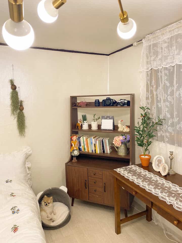 A cozy 6-tatami bedroom in white and wood tones featuring a bookshelf, desk, and a small dog in a pet bed with a natural style.