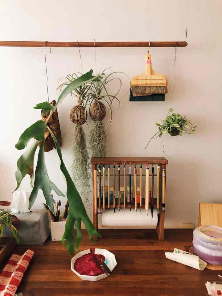 Natural color wood-tone desk workspace featuring various brushes and plants