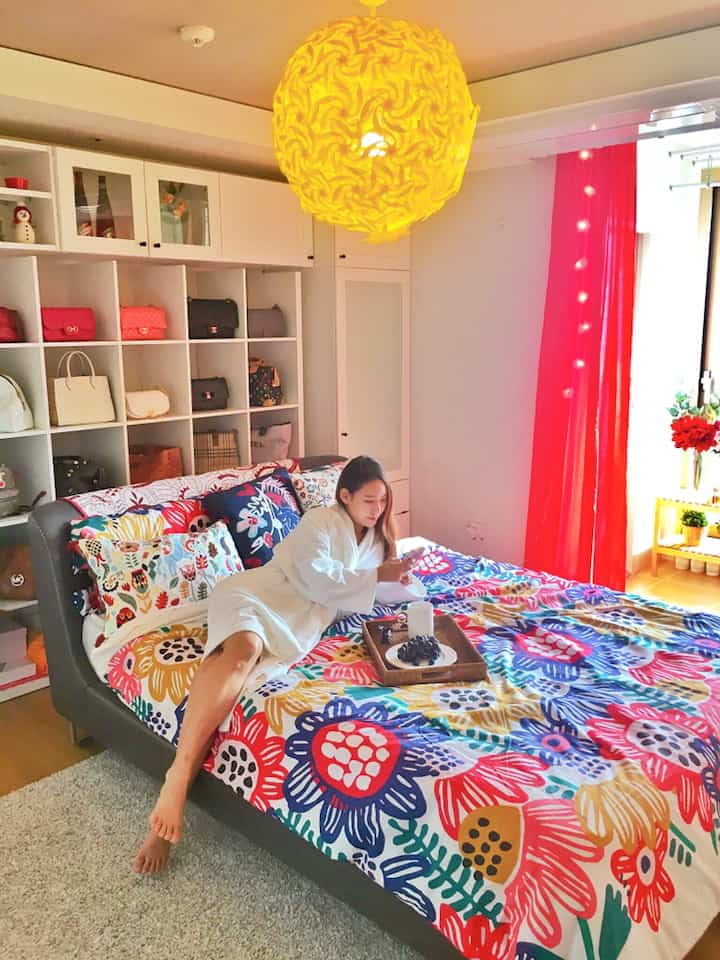 Bright beige floor and white walls in a bedroom featuring a modern bed with colorful floral bedding centrally placed