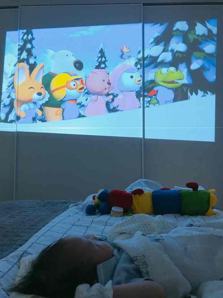 Blue-toned bedroom featuring baby bedding and blankets with home cinema projection