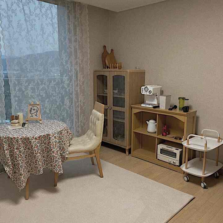 木目調と白を基調とした小さなアパートのおうちカフェ、レースカーテンと花柄テーブルクロスが温かみのある雰囲気を醸し出すインテリア