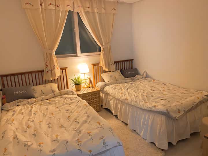 Warm natural tones and white bedroom featuring two beds with floral bedding creating a cozy atmosphere