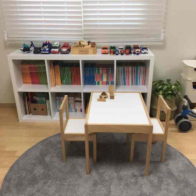 Natural tone kids' room featuring a small wooden table and chairs with organized shelves and toys creating a cozy space