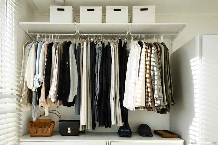 ホワイトとナチュラルカラーが基調のクローゼット、整理された洋服と収納が配置された雰囲気のあるインテリア