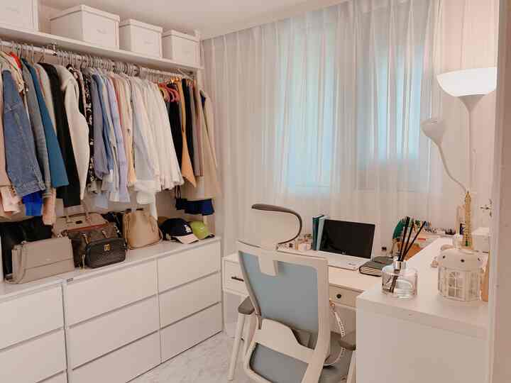 White-toned walk-in closet and home office space featuring organized dressers and desk with a cozy atmosphere