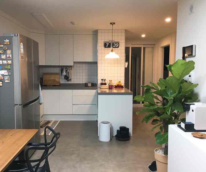 Bright white and natural tone kitchen and entrance, featuring a kitchen island and pendant light in a tidy space