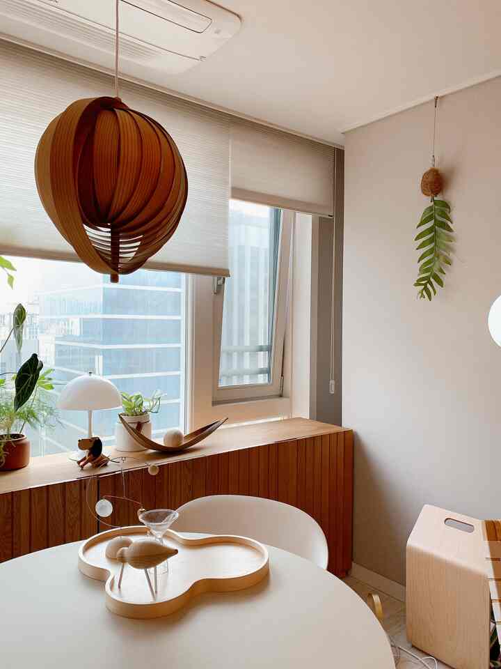 Natural wood tones and white dominate a living room featuring a round table and sideboard creating a clean, serene atmosphere