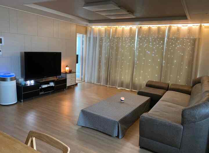 Warm wood-tone floor living room with gray sofa, TV stand, and soft ambient lighting