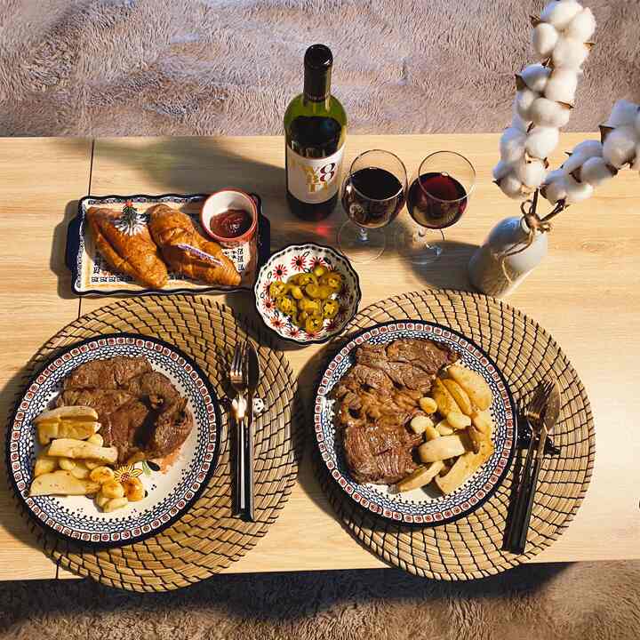 Natural-toned studio dining setting featuring patterned plates, wine glasses, and cotton flower decoration creating cozy home party vibe