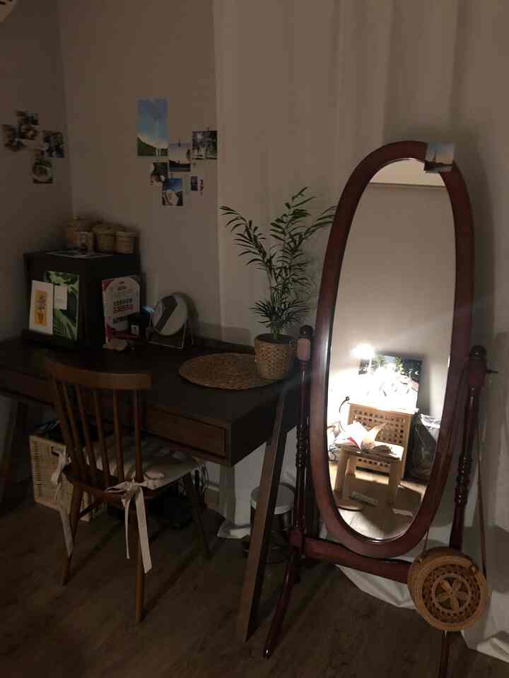 A cozy single household compact room with wood tone desk and a standing full-length mirror, embodying a natural color scheme