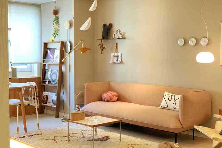 Warm beige-toned living room featuring a pink sofa with knot cushion and wooden furniture creating a cozy atmosphere
