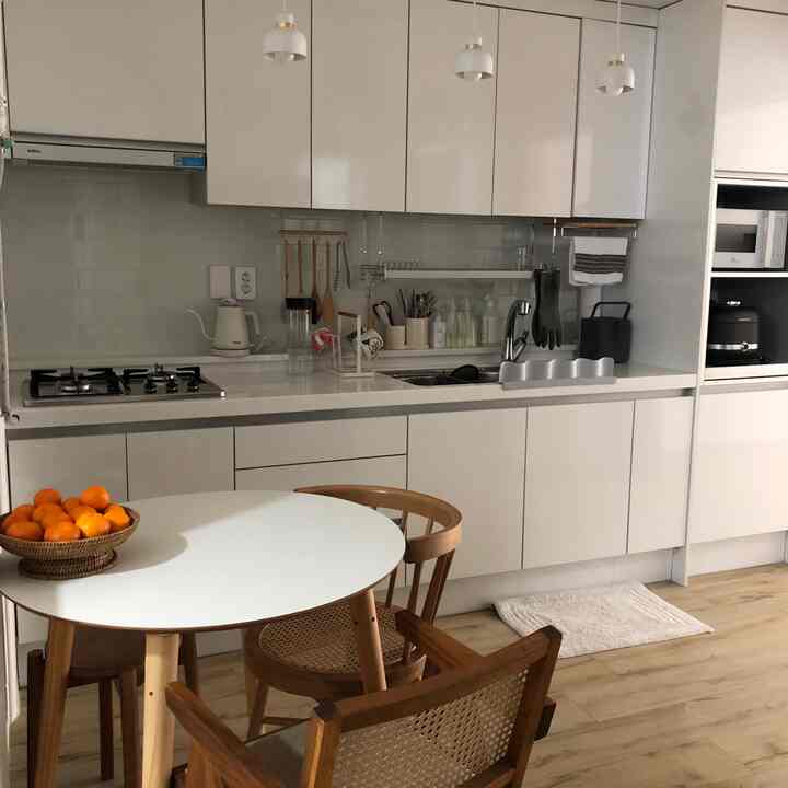 White and wood tone kitchen space featuring a round dining table and wooden chairs in a clean, natural modern style
