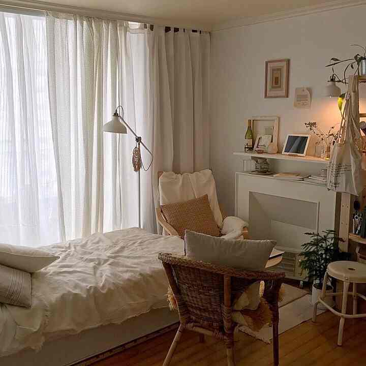 White and beige toned bedroom featuring an armchair and floor lamp with a cozy natural atmosphere