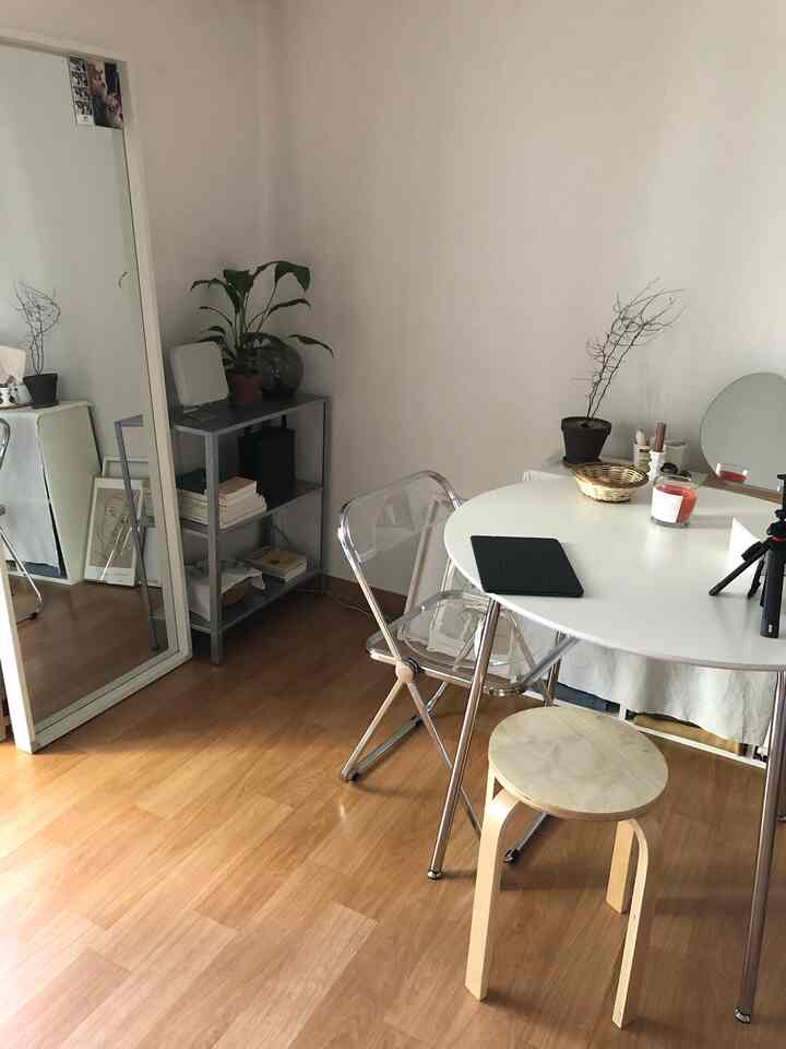 白と木目調が調和したコンパクトなリビング、丸テーブルとメタルシェルフ、姿見が配置された雰囲気のあるインテリア